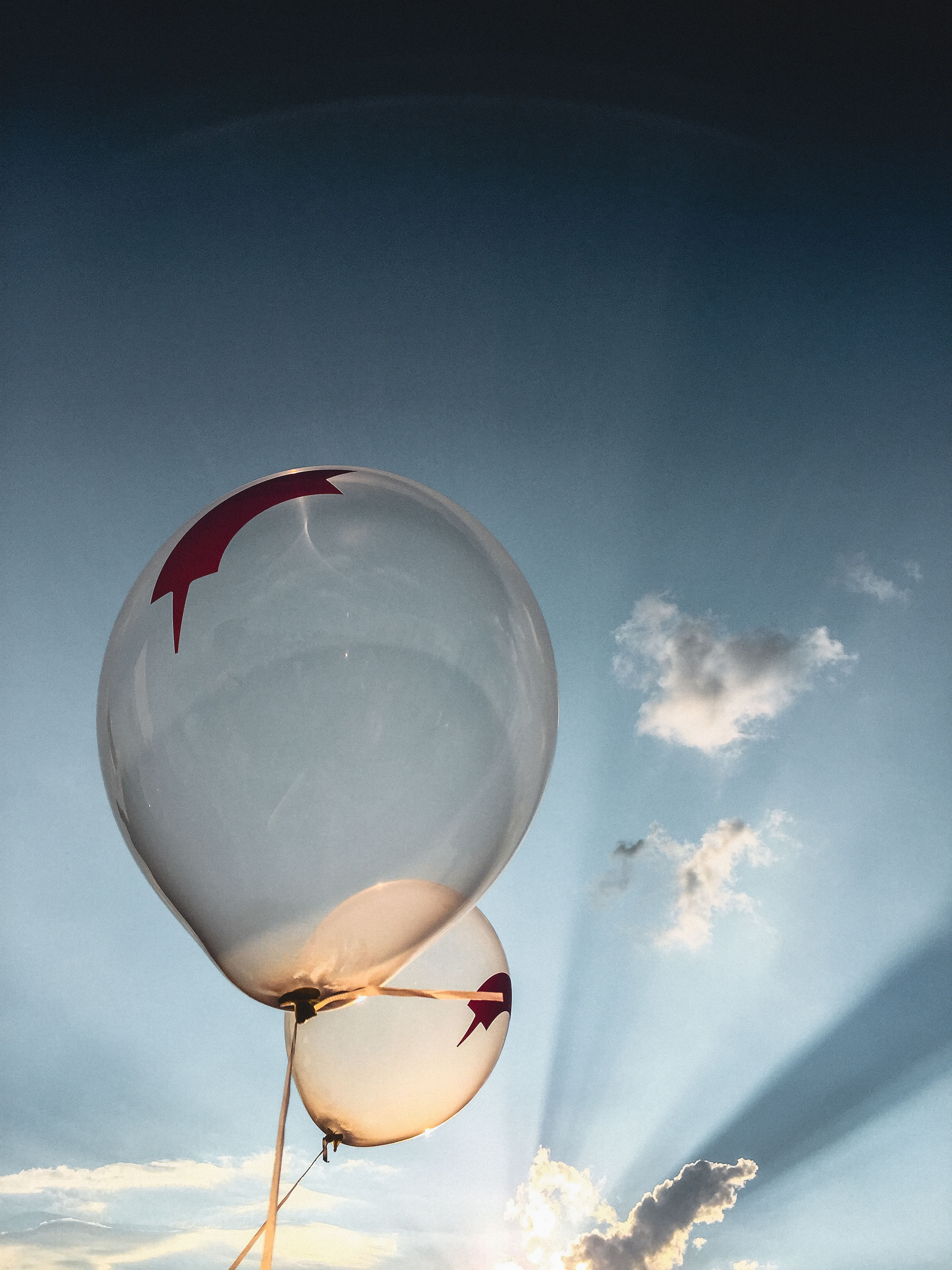 Zwei Luftballons werfen im Dunst einen Lichtschatten auf den Himmel.