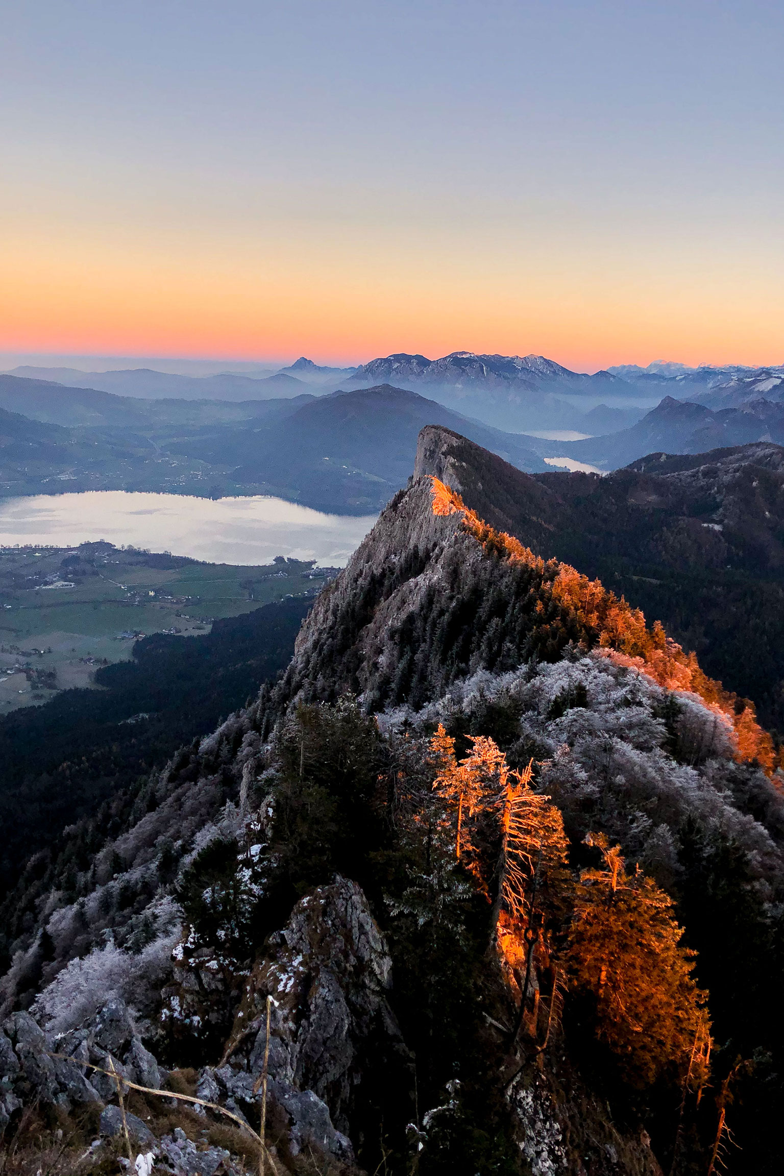 Blick vom Gipfel des Schobers bei Sonnenuntergang auf einen Teil des Mondsees in Salzburg, Österreich.