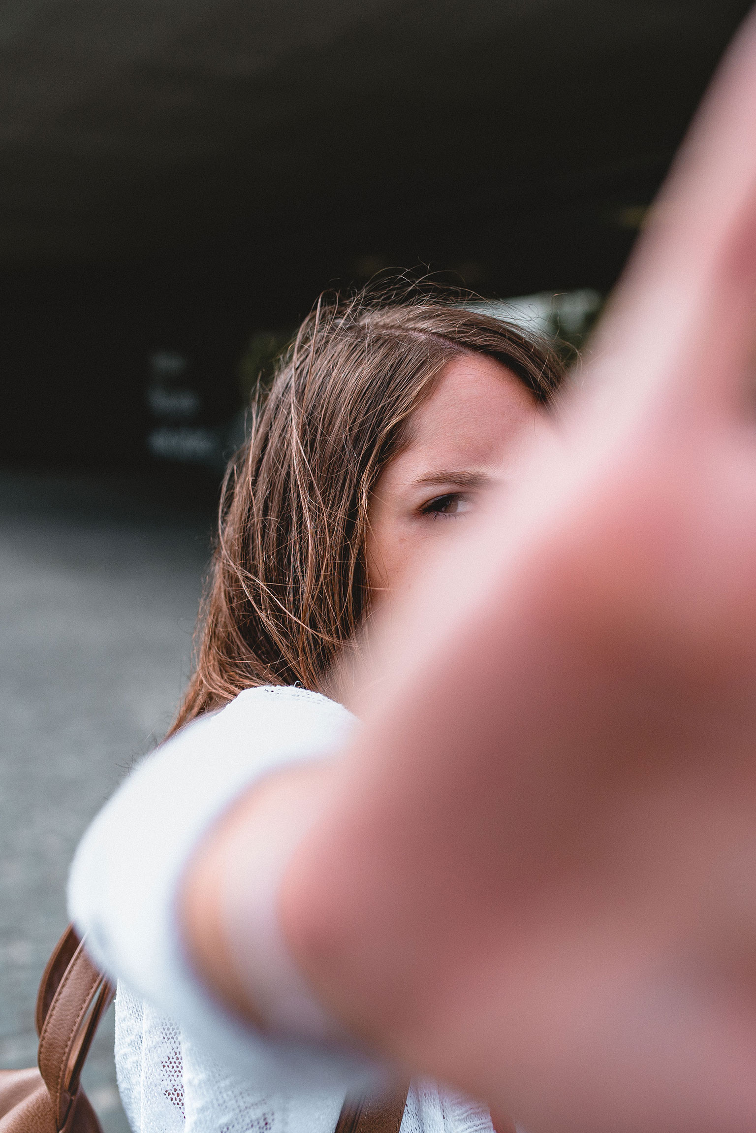 Portrait einer Frau, in dem sie ihre ausgestreckte Hand vor das rechte Augen hält.