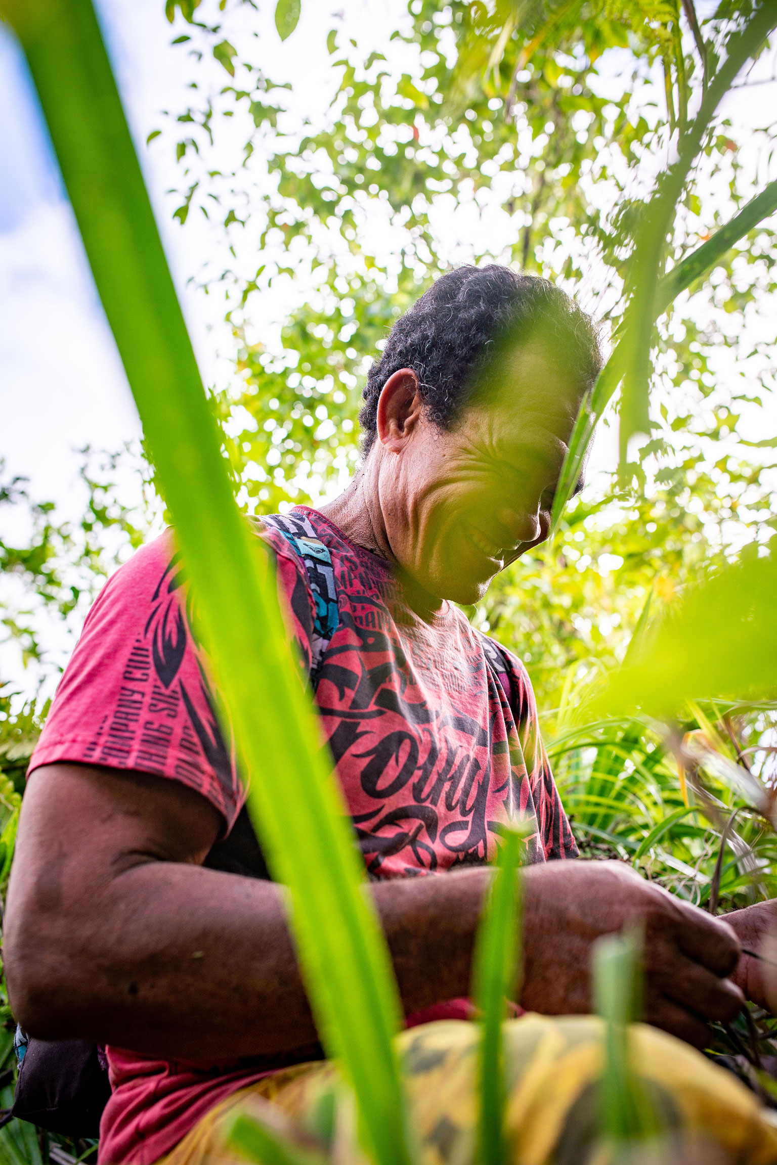Portrait durch Dschungelgras eines Trägers bei einer Expedition zu einem abgelegen Vulkansees auf Samoa.