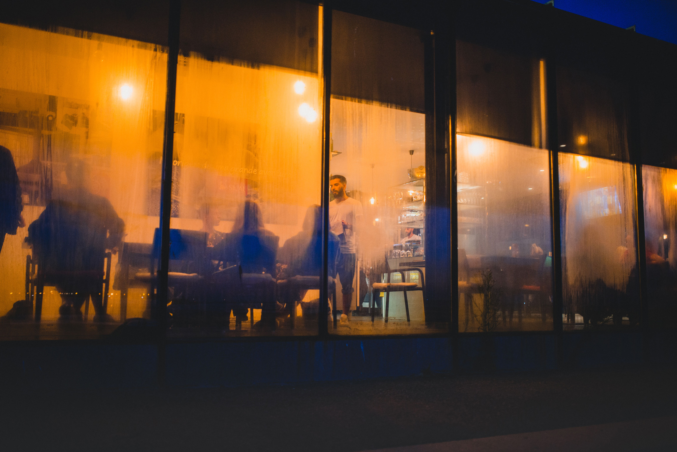 Blick bei Nacht durch die durch Kondenswasser angelaufenen Scheiben eines Restaurants.